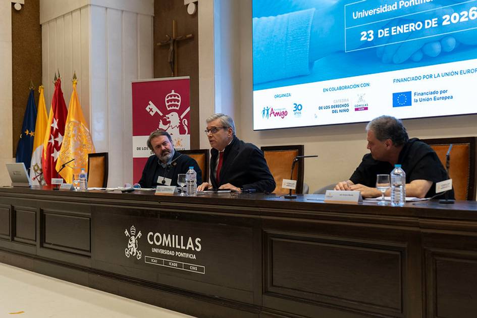 Una mesa redonda en la Universidad Pontificia Comillas con varios ponentes y banderas al fondo.
