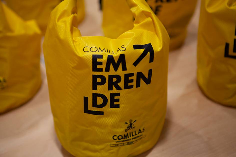 Una bolsa amarilla con la palabra 'Emprende' destacada en negro.