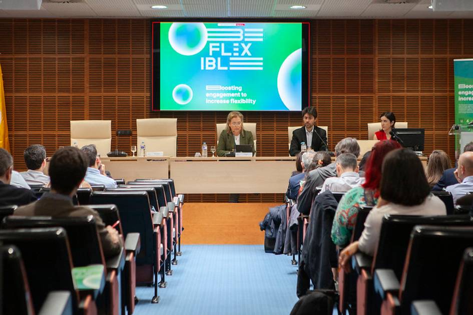 Un evento en una sala con un panel de oradores y público sentado.