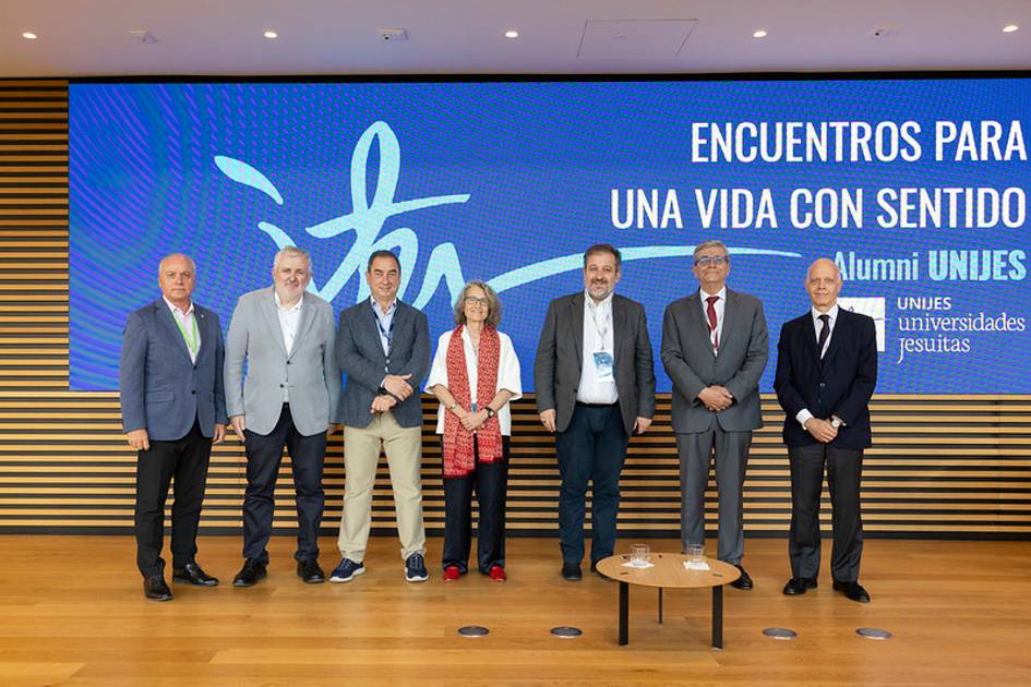 Un grupo de personas posa frente a una pantalla con el lema 'Encuentros para una vida con sentido'.