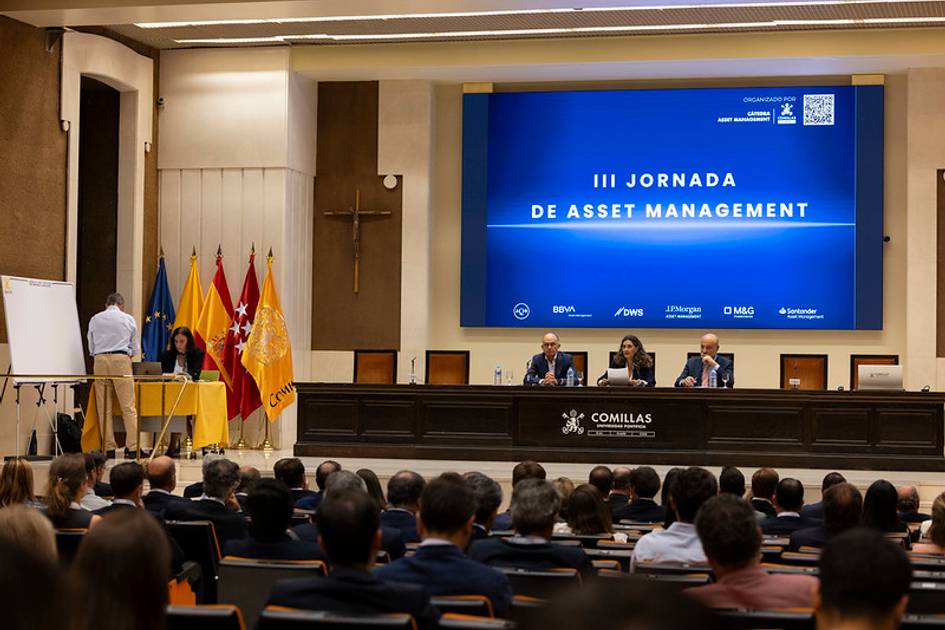 La imagen muestra un evento académico sobre gestión de activos con varios ponentes en el escenario y una audiencia atenta.