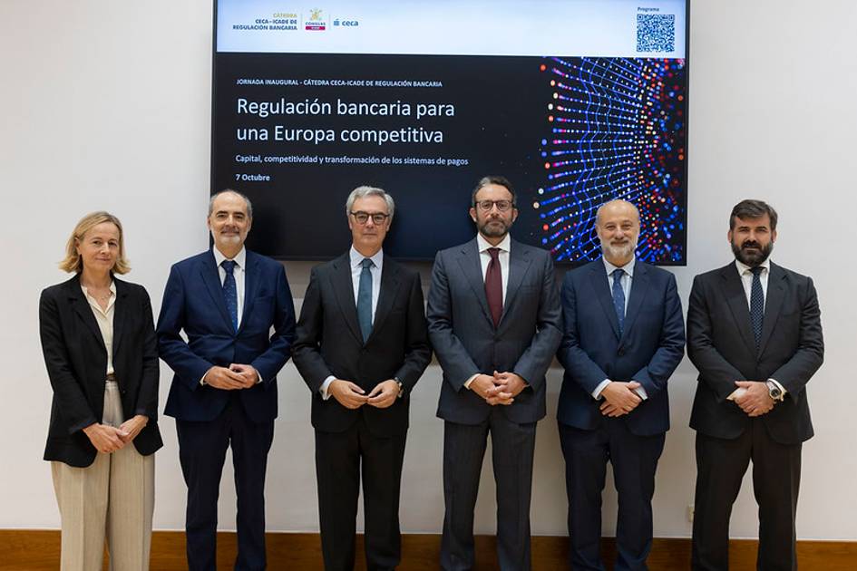 Un grupo de personas posando frente a una pantalla que muestra un evento sobre regulación bancaria en Europa.