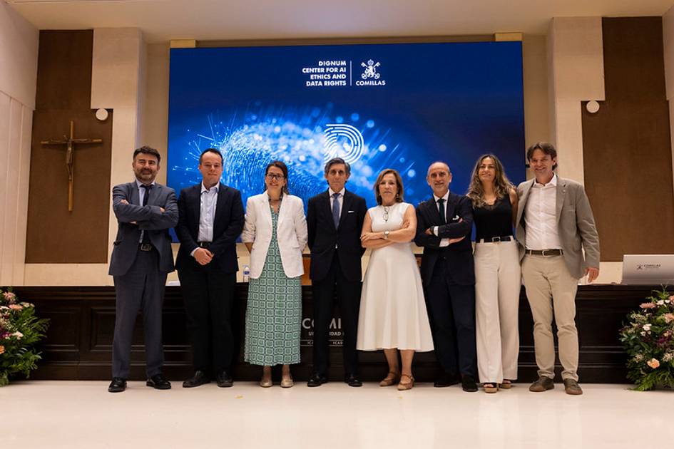 Grupo de personas posando frente a una pantalla en un evento formal.