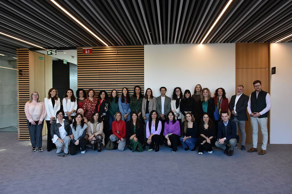 Un grupo de personas posando sonrientes para una fotografía en un pasillo moderno de oficinas.