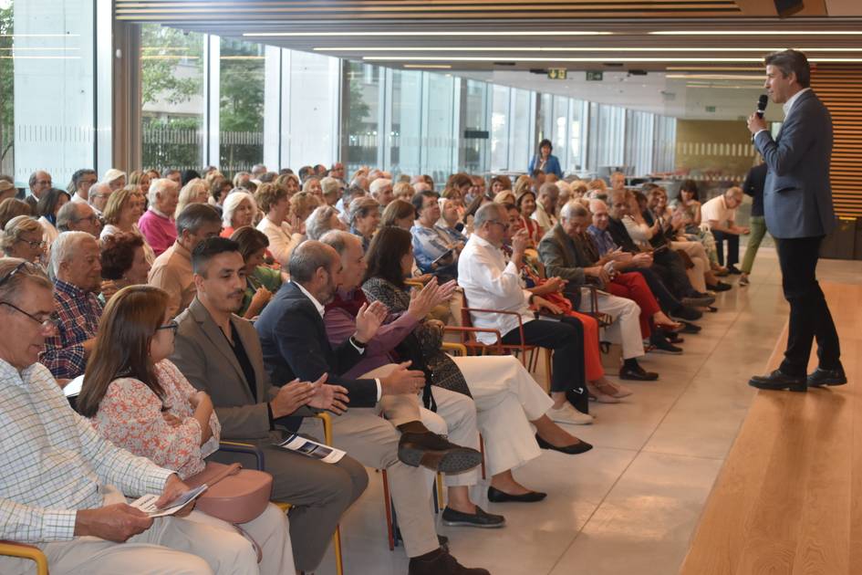 Un orador se dirige a una gran audiencia de personas mayores en un evento interior.