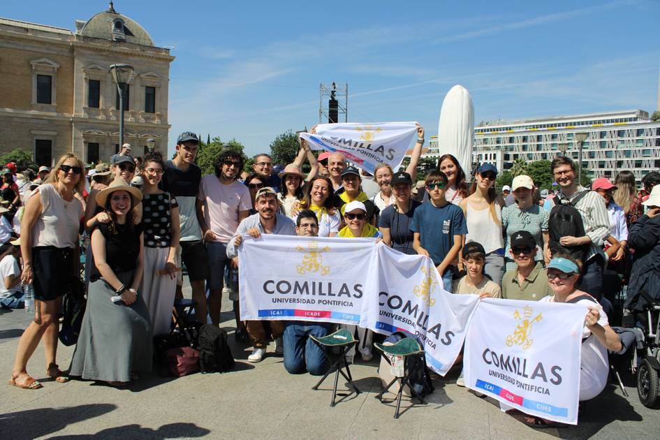 Grupo de estudiantes de la Universidad Pontificia Comillas posando juntos al aire libre con banderas de su institución.