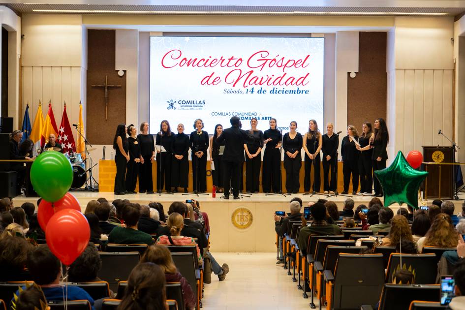 Un grupo de personas está en un escenario durante un concierto de gospel de Navidad en un auditorio con público sentado.