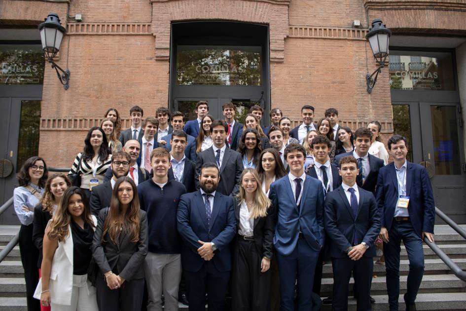 Grupo de personas posando en una escalera frente a un edificio.