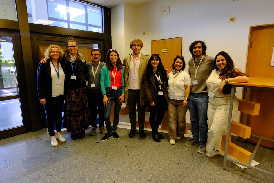 Un grupo de diez personas posando juntas en un edificio, sonriendo y con ropa casual.