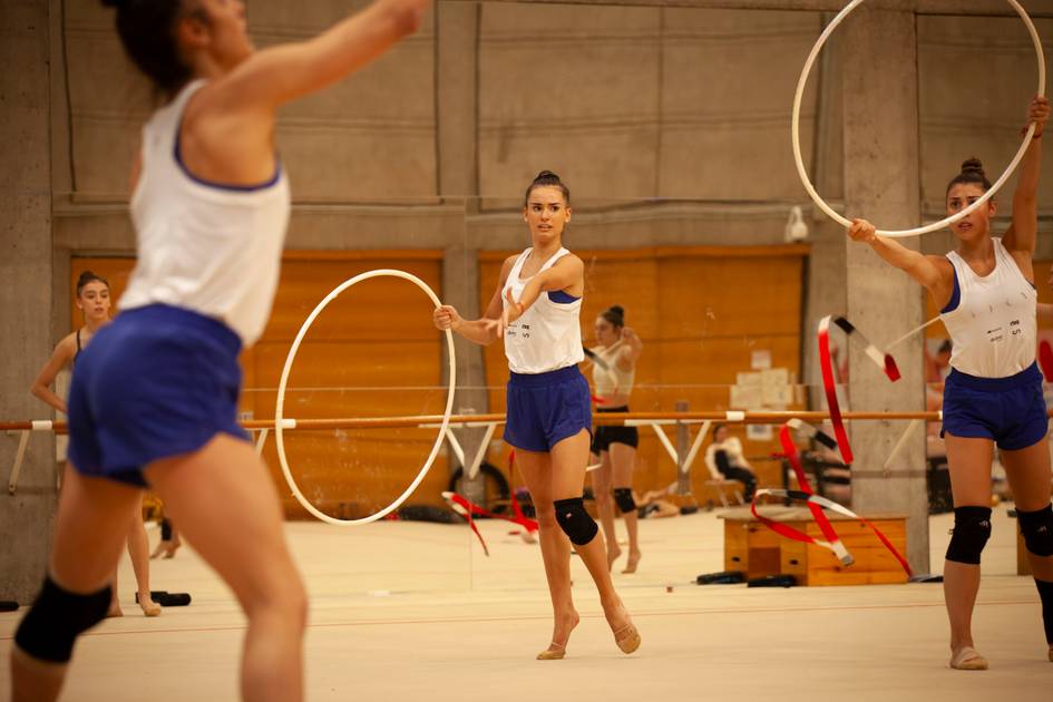 Un grupo de gimnastas realizan ejercicios con aros en un gimnasio.