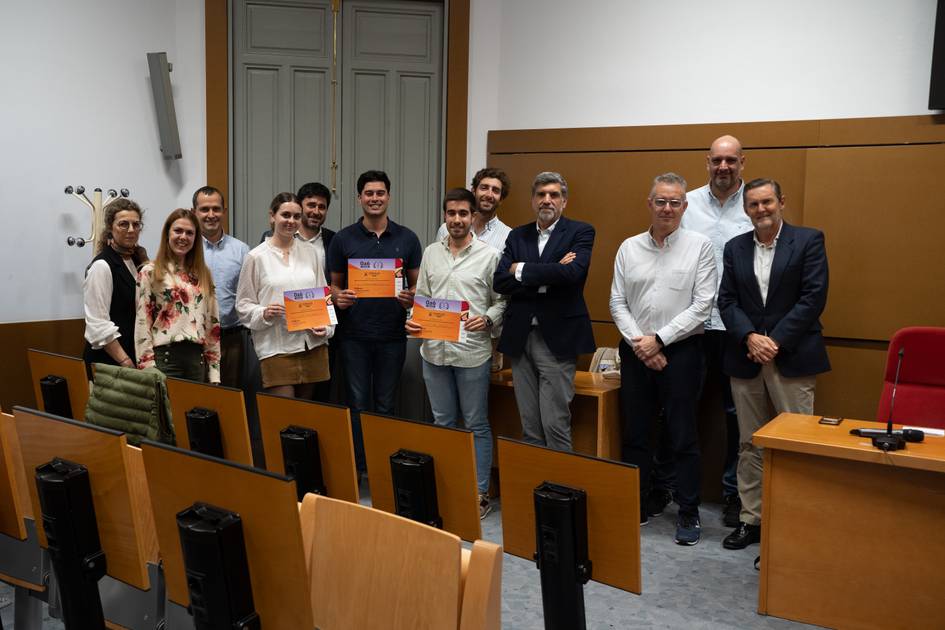 Un grupo de personas sonríe mientras sostiene certificados en un aula.