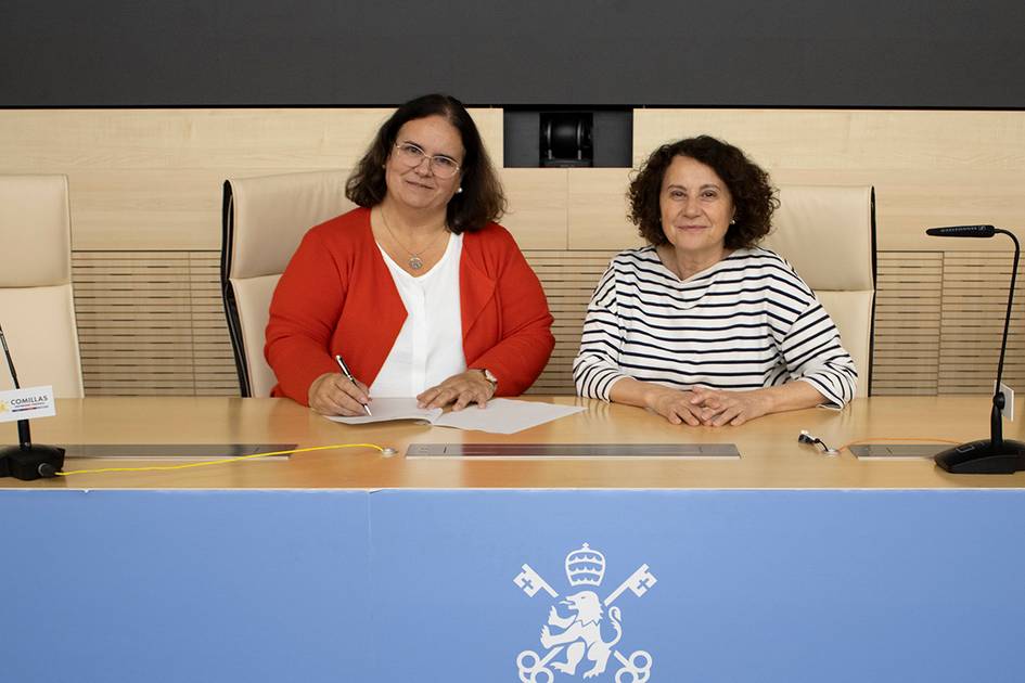 Dos mujeres sentadas en una mesa firmando documentos en un entorno oficial.