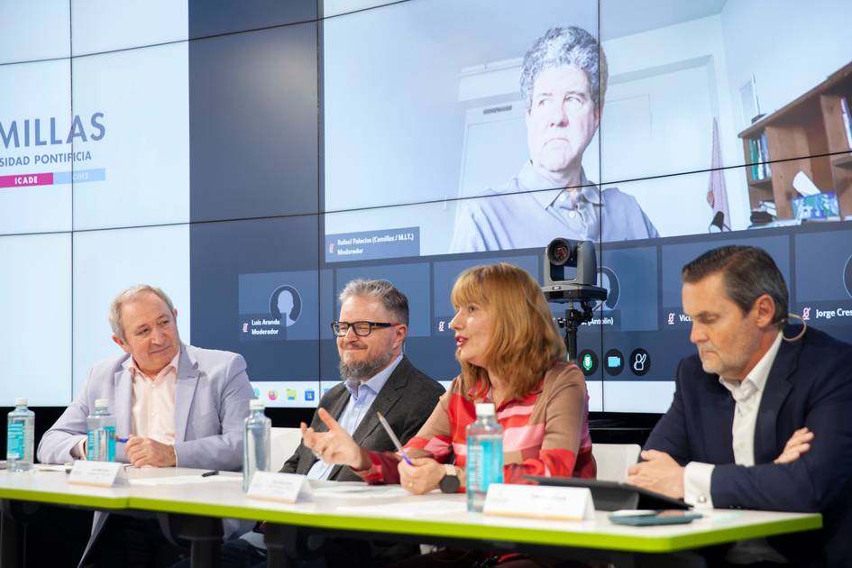 Una mesa de discusión con varios ponentes y una presentación en pantalla.