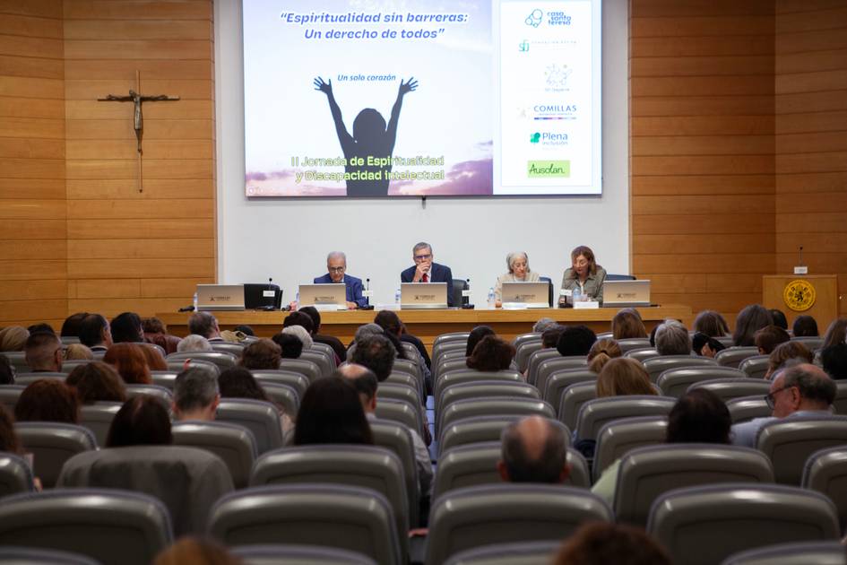 Una conferencia sobre espiritualidad con un auditorio sentado y tres ponentes en el escenario.