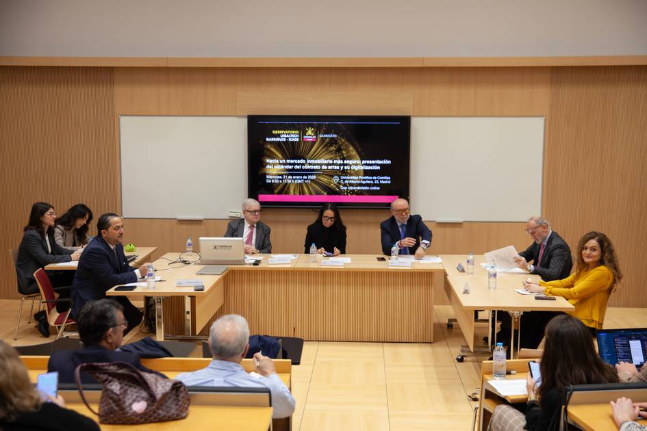 Una reunión en una sala moderna con varias personas sentadas alrededor de una mesa.