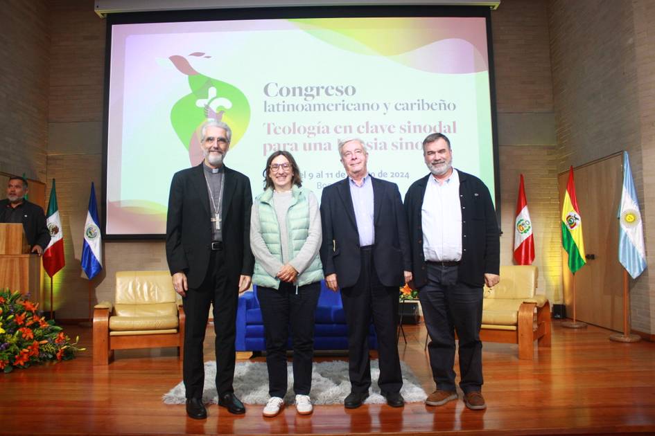 Four people standing in front of a presentation screen at a Latin American and Caribbean theology congress.