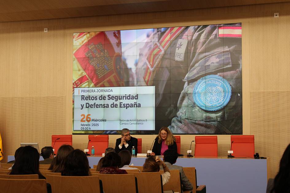 Imagen de una jornada sobre seguridad y defensa en España con participantes en un panel y una presentación en pantalla.