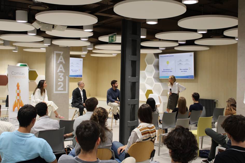 A professional presentation in a modern office space with an audience and several speakers.