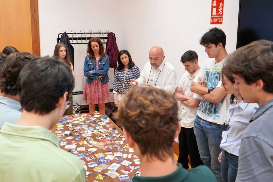 Un grupo de personas observa atentamente una mesa llena de tarjetas en un entorno de aula.