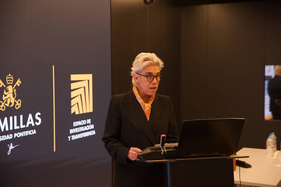 Una mujer con cabello canoso está hablando frente a un podio en un evento formal.