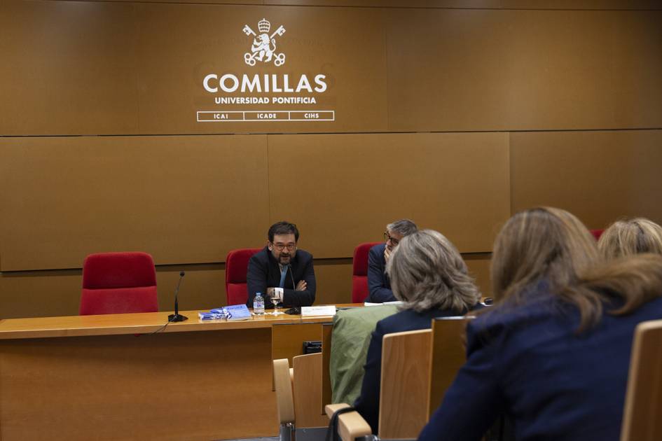 Un panel de discusión en la Universidad Pontificia Comillas con varios participantes sentados.