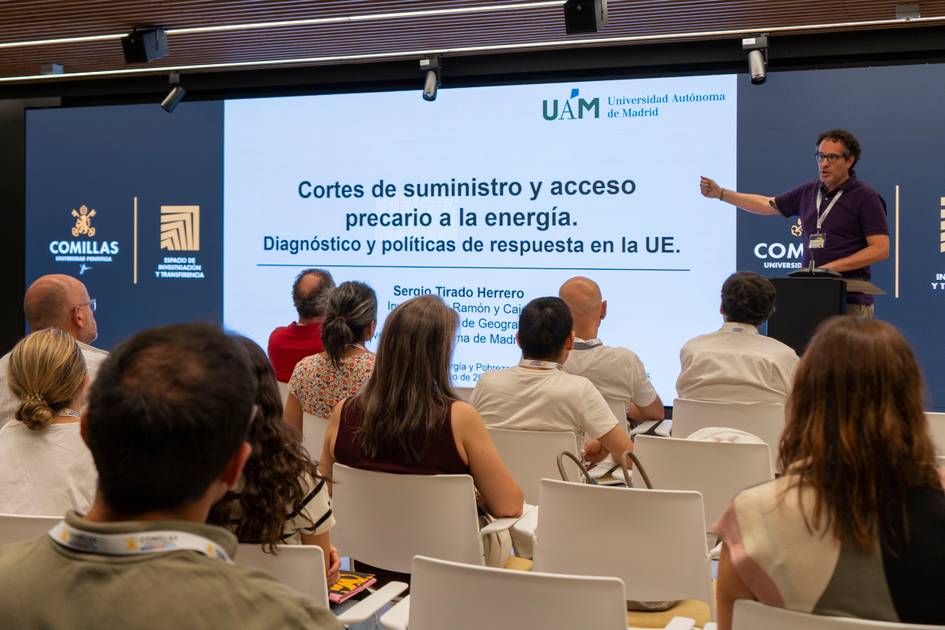 Un ponente presenta un tema sobre cortes de suministro y acceso a la energía ante un público atento en un evento académico.