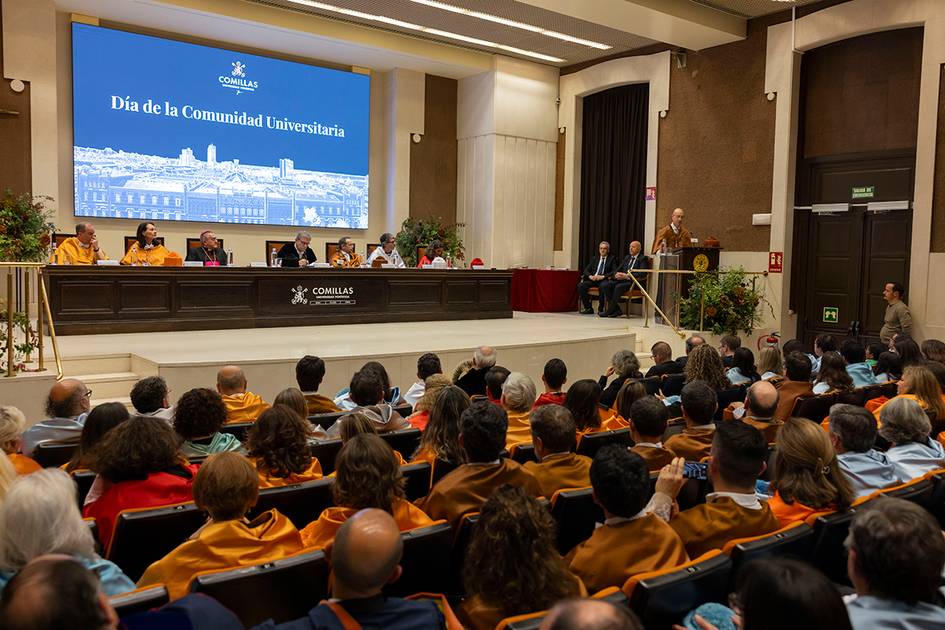 Una ceremonia del Día de la Comunidad Universitaria con un público atento y un panel de oradores en el escenario.