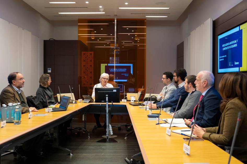 Un grupo de profesionales sentados alrededor de una mesa de conferencias en una reunión de negocios con un proyector mostrando una presentación.