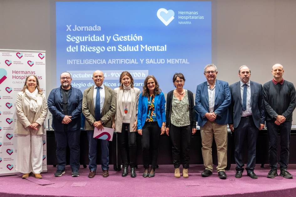 A group of eight people, standing in front of a presentation screen at a conference focused on mental health risk management and artificial intelligence.