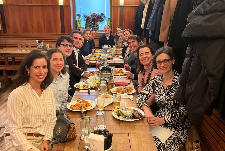 Una grupo de personas disfrutando de una comida en una mesa larga.