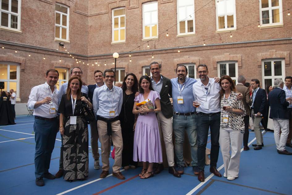 A group of people smiling and posing together at an outdoor event in the evening.