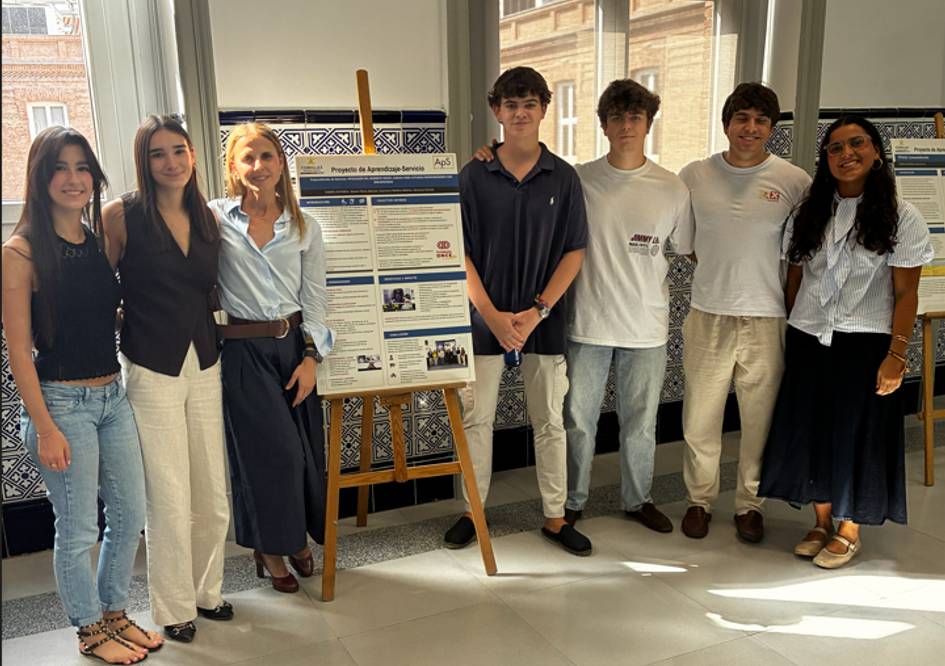 Un grupo de jóvenes se encuentra posando junto a un cartel en un espacio moderno.