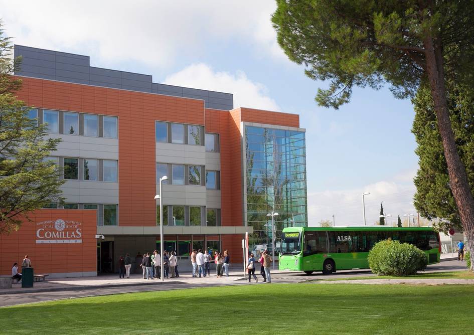 Modern university building with students walking in front and a green bus parked nearby.