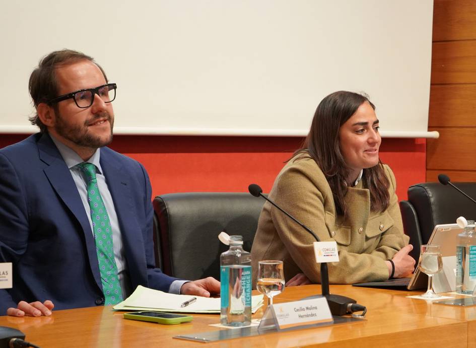 Dos personas sentadas en una mesa en un evento de presentación.