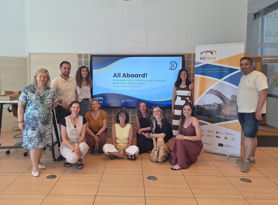 Un grupo de personas sonrientes posan frente a una pantalla con un mensaje sobre un proyecto llamado 'All Aboard'.