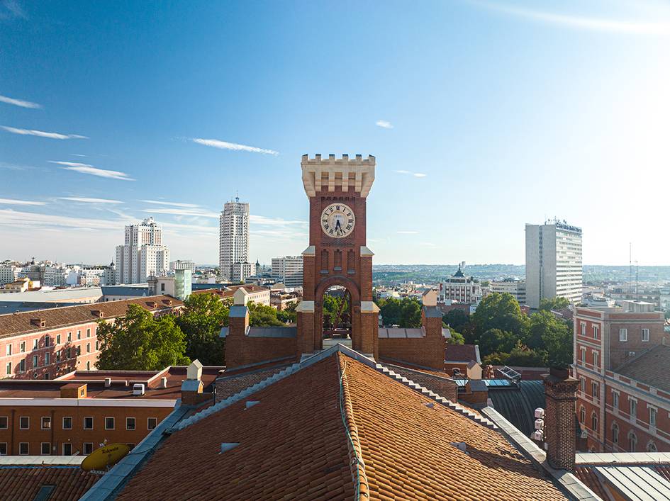 Vista panorámica de una ciudad con un reloj prominente y edificios modernos al fondo.