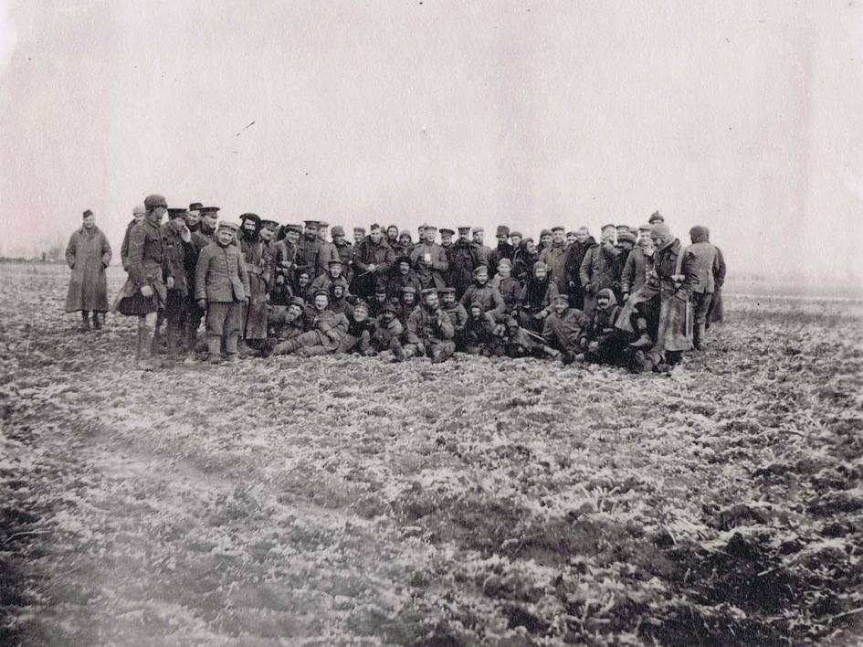 Grupo de soldados posando en un campo embarrado.