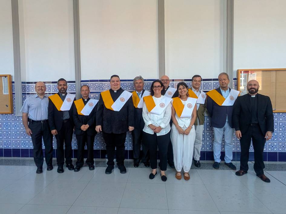 Grupo de personas posando en una sala, todas con batas y sashes distintivos.