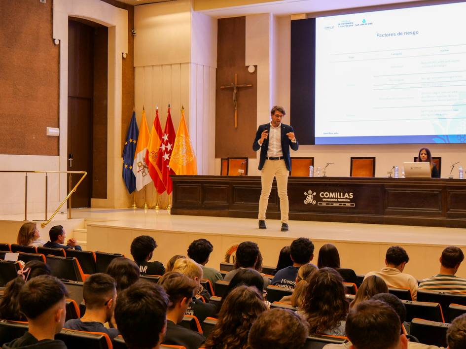 Un ponente da una charla frente a un auditorio lleno de estudiantes en un evento educativo.