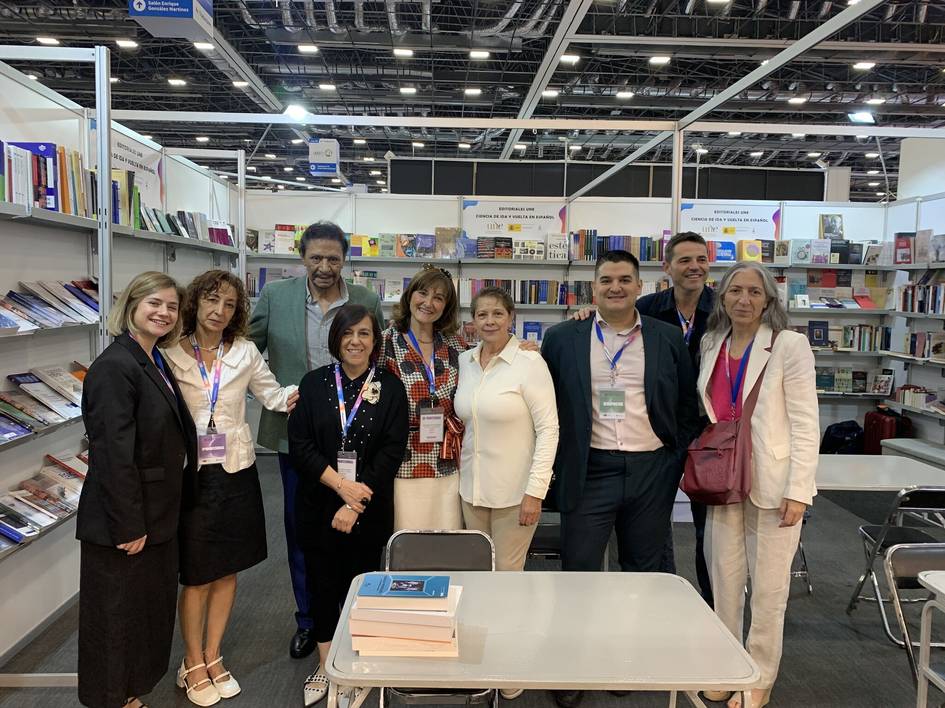 Un grupo de ocho personas sonriendo en un stand de libros en un stand de la Feria del Libro de Guadalajara 2024