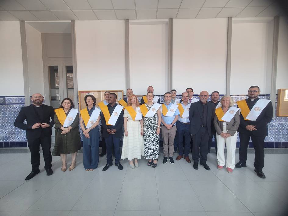 Grupo de personas posando con sábanas amarillas y blancas en un evento formal.