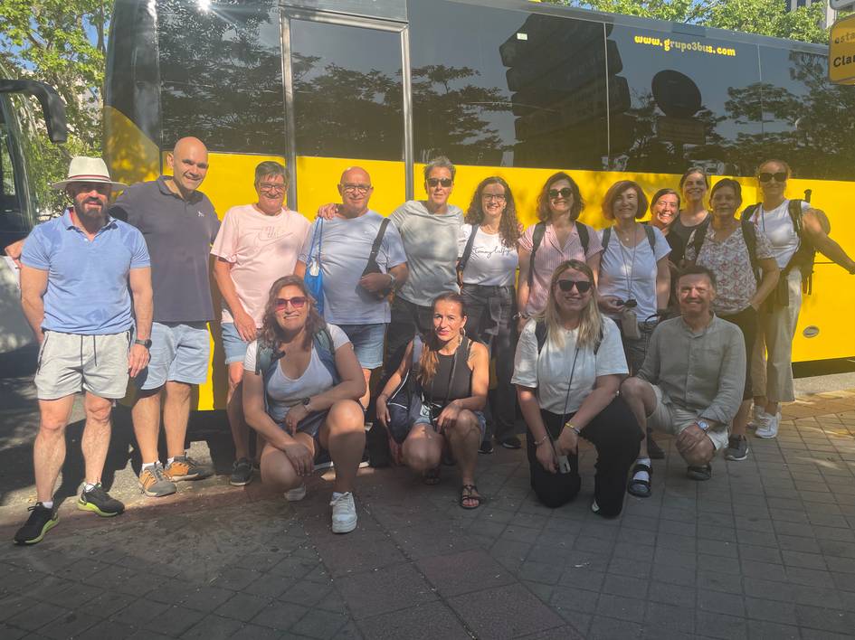 Grupo de personas posando frente a un autobús amarillo.