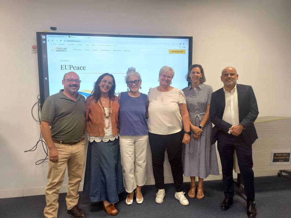 Seis personas posan sonrientes frente a una pantalla que muestra un sitio web relacionado con EUPeace.