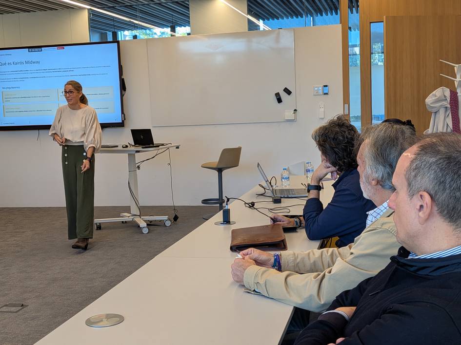 Una presentadora expone frente a un grupo de personas en un aula moderna.
