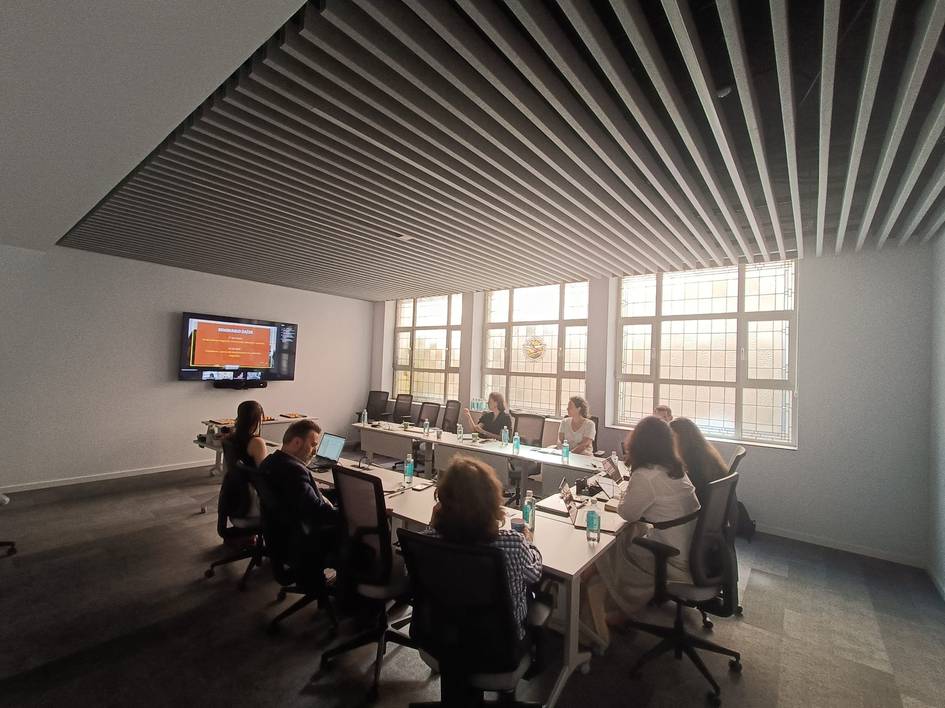 Una reunión en una sala moderna con varias personas sentadas alrededor de una mesa.