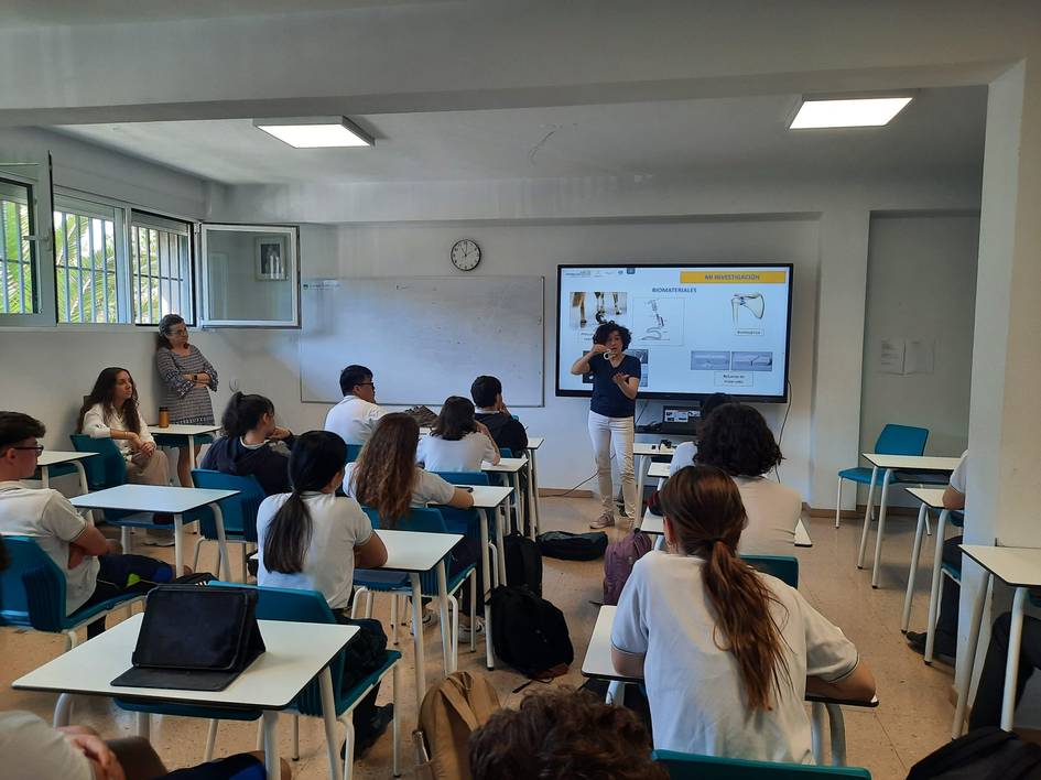 A teacher presenting a slide about atomic structure to students in a classroom.