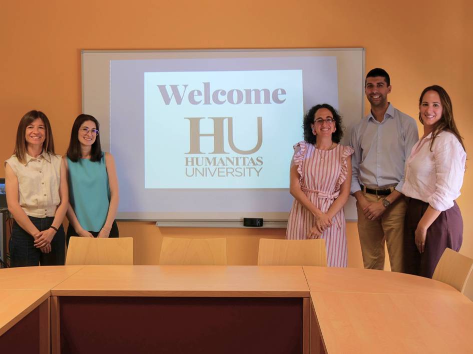 Un grupo de cinco personas sonríe frente a una pantalla que dice 'Welcome HU HUMANITAS UNIVERSITY'.