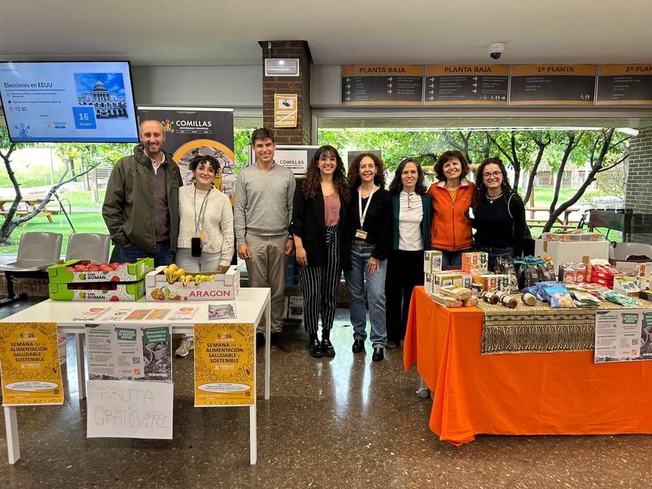 A group of people standing behind a table with various products at an indoor event.