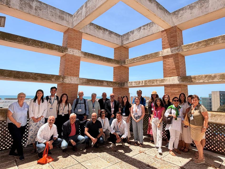 Grupo de personas posando en una terraza con un paisaje al fondo.
