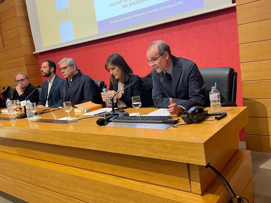 Una mesa de debate con cinco personas sentadas frente a un público en un evento académico.